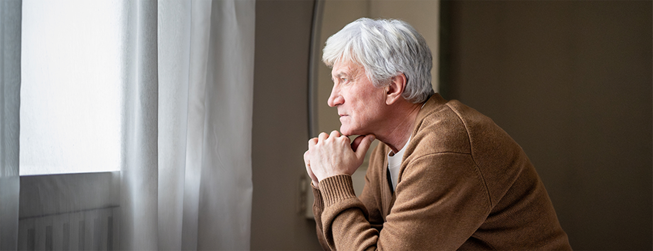 Image of senior man alone and looking out the window